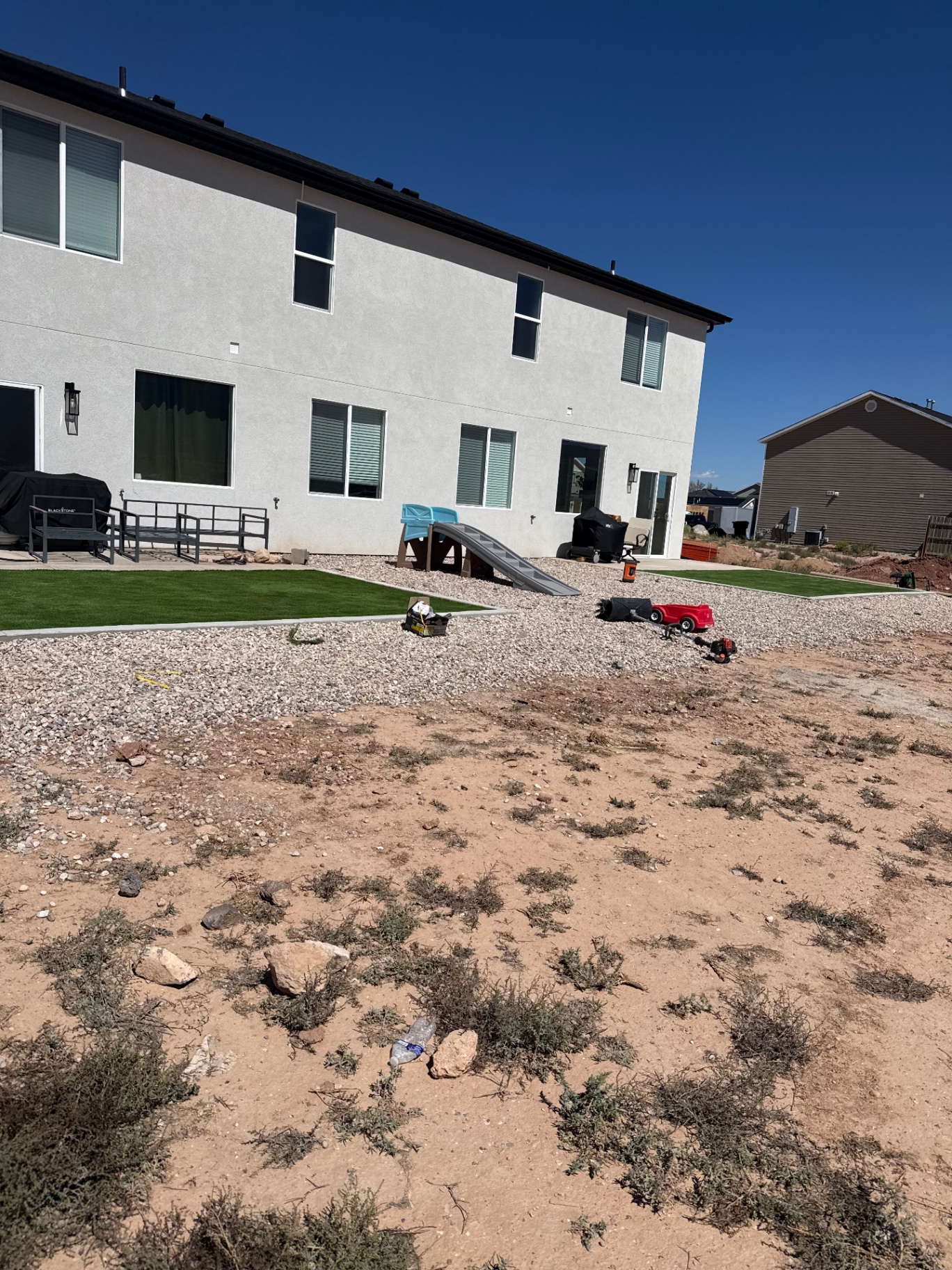 Finished backyard with artificial turf, concrete edging and decorative rock