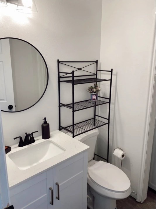 Remodeled guest bathroom with round mirror, white vanity and black fixtures
